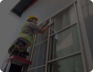 A man on a ladder repairing a window.