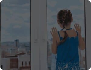 A little girl gazing out of a window, her eyes filled with wonder and curiosity.